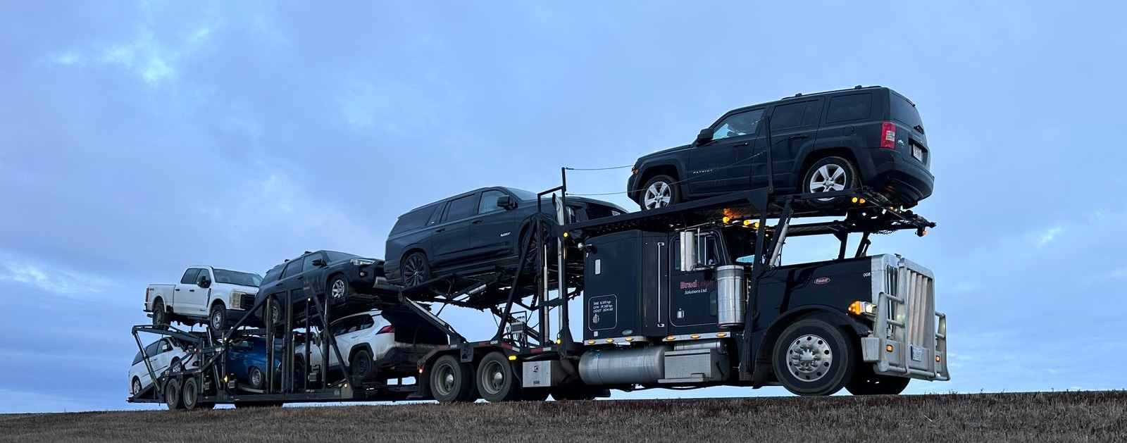 BradLeigh Solutions car hauler loaded with vehicles at dusk
